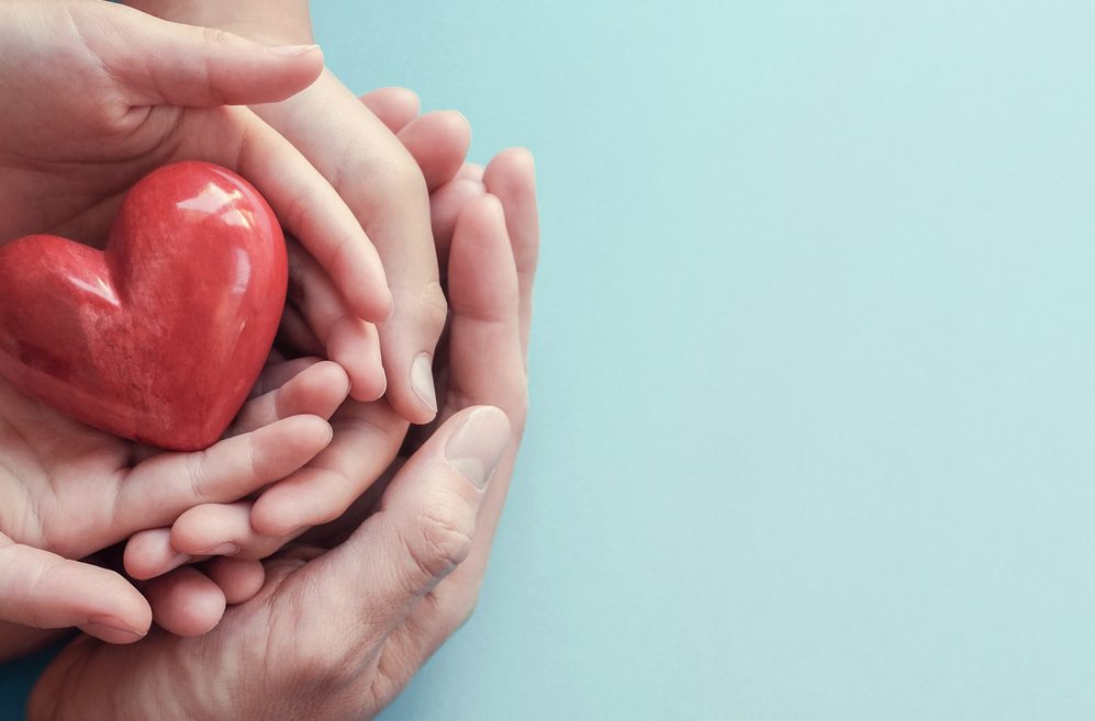 Adult and child hands holding red heart