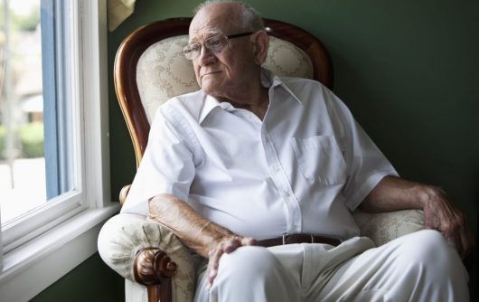 Senior Man sitting in chair looking out window