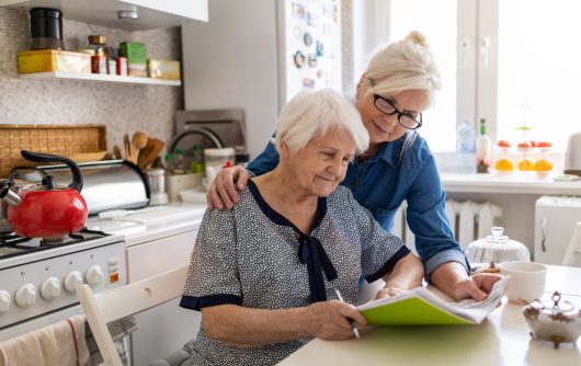 Mature woman helping elderly mother with paperwork