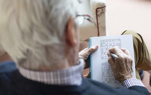 Senior Man Doing Sudoku Puzzle At Home