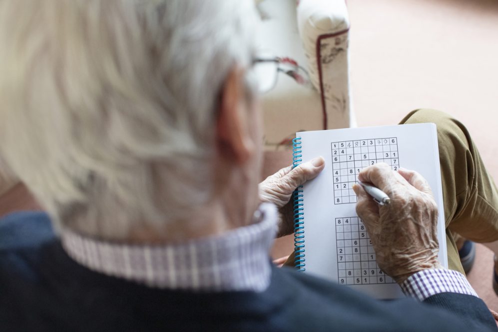 Senior Man Doing Sudoku Puzzle At Home