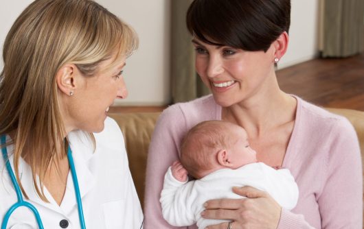 Mother with newborn baby visiting with a health professional