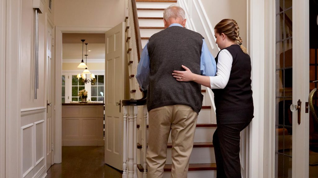 Caregiver assisting client up the stairs