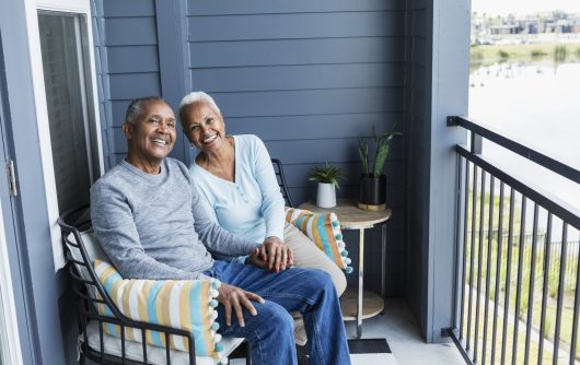 Senior couple relaxing on porch, holding hand, smiling