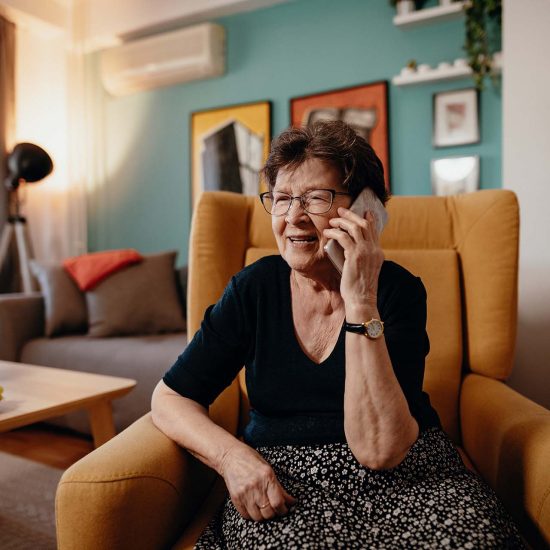 Portrait of senior woman at home using mobile phone and technologies