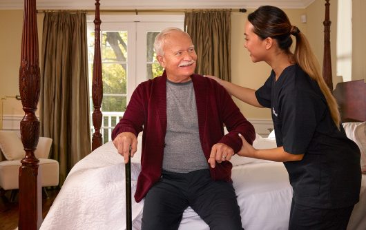 Caregiver helping senior man out of bed