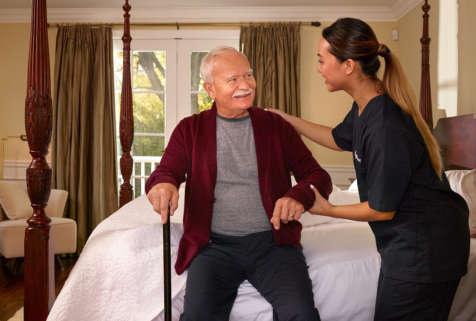 Caregiver helping senior man out of bed