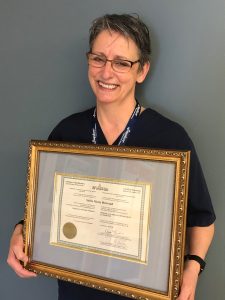 Sylvia Bertrand holds up her framed certificate of qualification