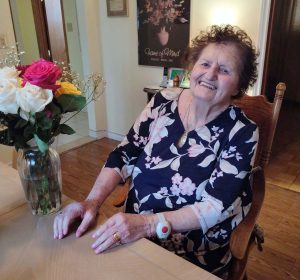 Teresa sitting happily at her table at home 