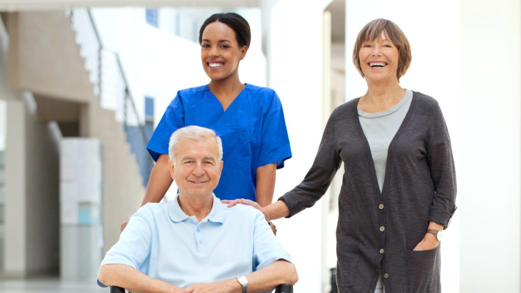 Infirmière aidant un patient en fauteuil roulant et sa femme