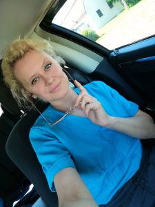 Blonde woman in blue sitting in her car