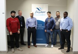 Les membres de l'équipe informatique de Bayshore et John Lawrence devant la bannière de la Fondation Bayshore.