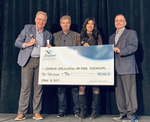 Four people standing on stage with giant cheque