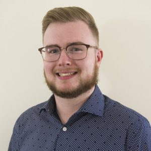 Homme souriant avec des lunettes à la caméra.