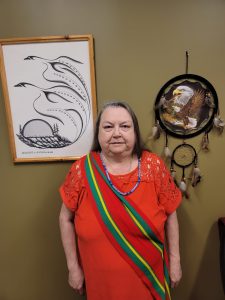 Woman in red in front of indigenous artwork