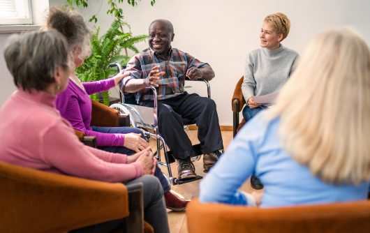 A group of diverse older people chatting with a counsellor during a therapy session in a residential care home