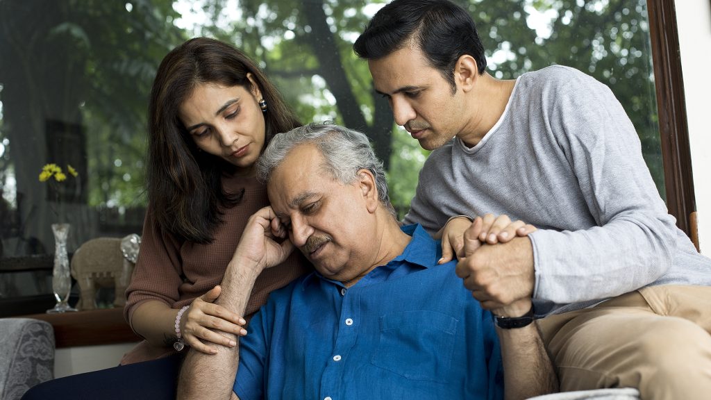 Couple comforting depressed old father at home