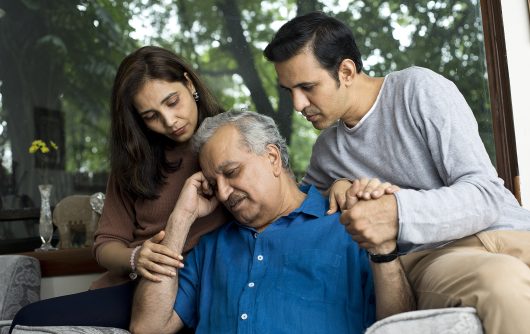 Couple comforting depressed old father at home