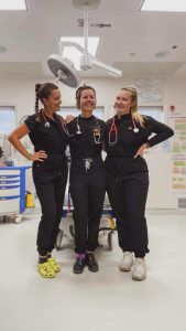 Three female nurses smiling and posing for a photo in a hospital room