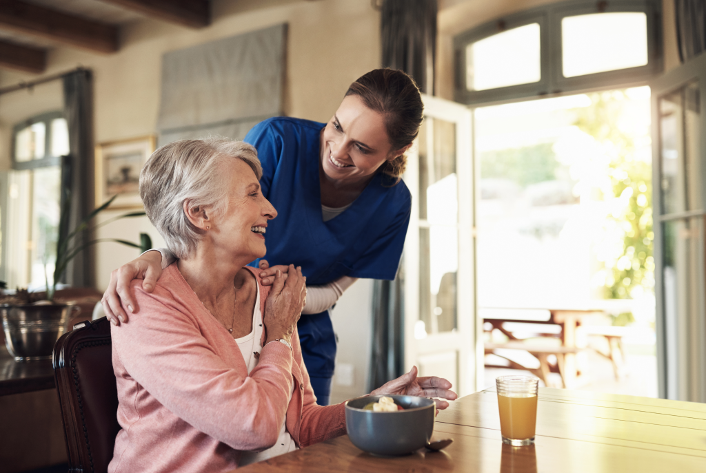 Young nurse checking up on a senior woman during breakfast at a nursing home