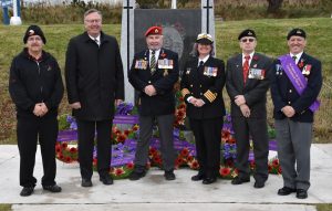 Military personnel posing in front of war memorial in on remembrance day