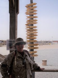 A woman in military clothing posing infront of a sign