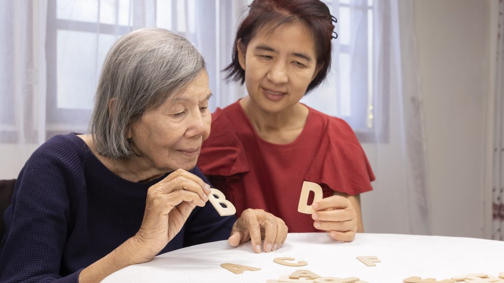 Elderly woman playing alphabet games for improve mental health and memory with daughter