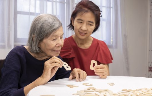 Elderly woman playing alphabet games for improve mental health and memory with daughter