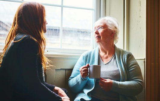Older woman talking with her young daughter at home