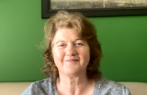 A woman sitting on a couch against a green wall.