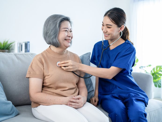 Nurse at nursing home taking care of senior elderly woman