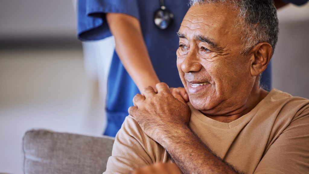 Nurse or doctor offer their man support during recovery or loss. Caregiver holding hand of her sad senior patient and showing kindness while doing a checkup at a retirement, old age home or hospital