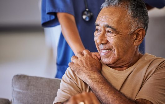 Nurse or doctor offer their man support during recovery or loss. Caregiver holding hand of her sad senior patient and showing kindness while doing a checkup at a retirement, old age home or hospital