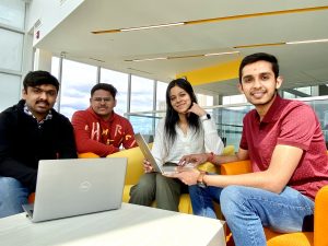 A group of four students sitting and posing for a group photo