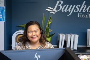 Woman behind computer smiling at camera