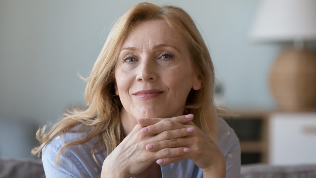 middle-aged woman resting on sofa look at camera