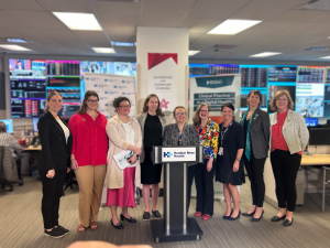 Group of Nurses in plain clothing posing for photo behind podium