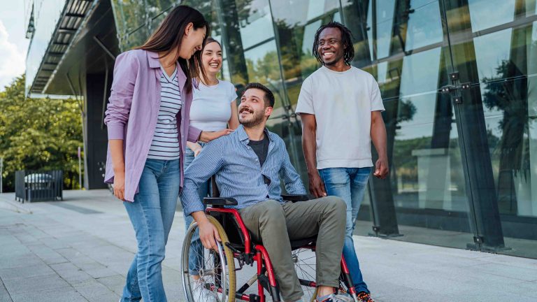 Man in a wheelchair talking to three friends