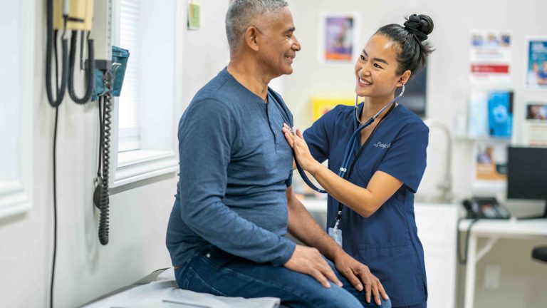 Caregiver examining a man with a stethoscope
