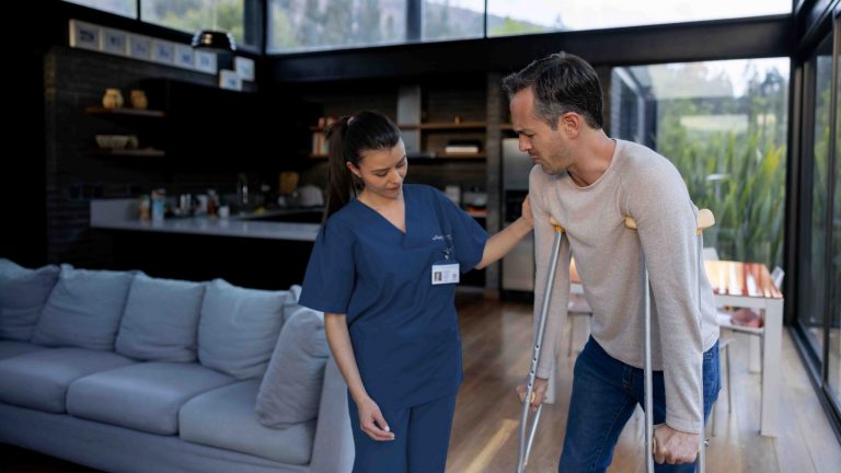 Caregiver helping a man with crutches