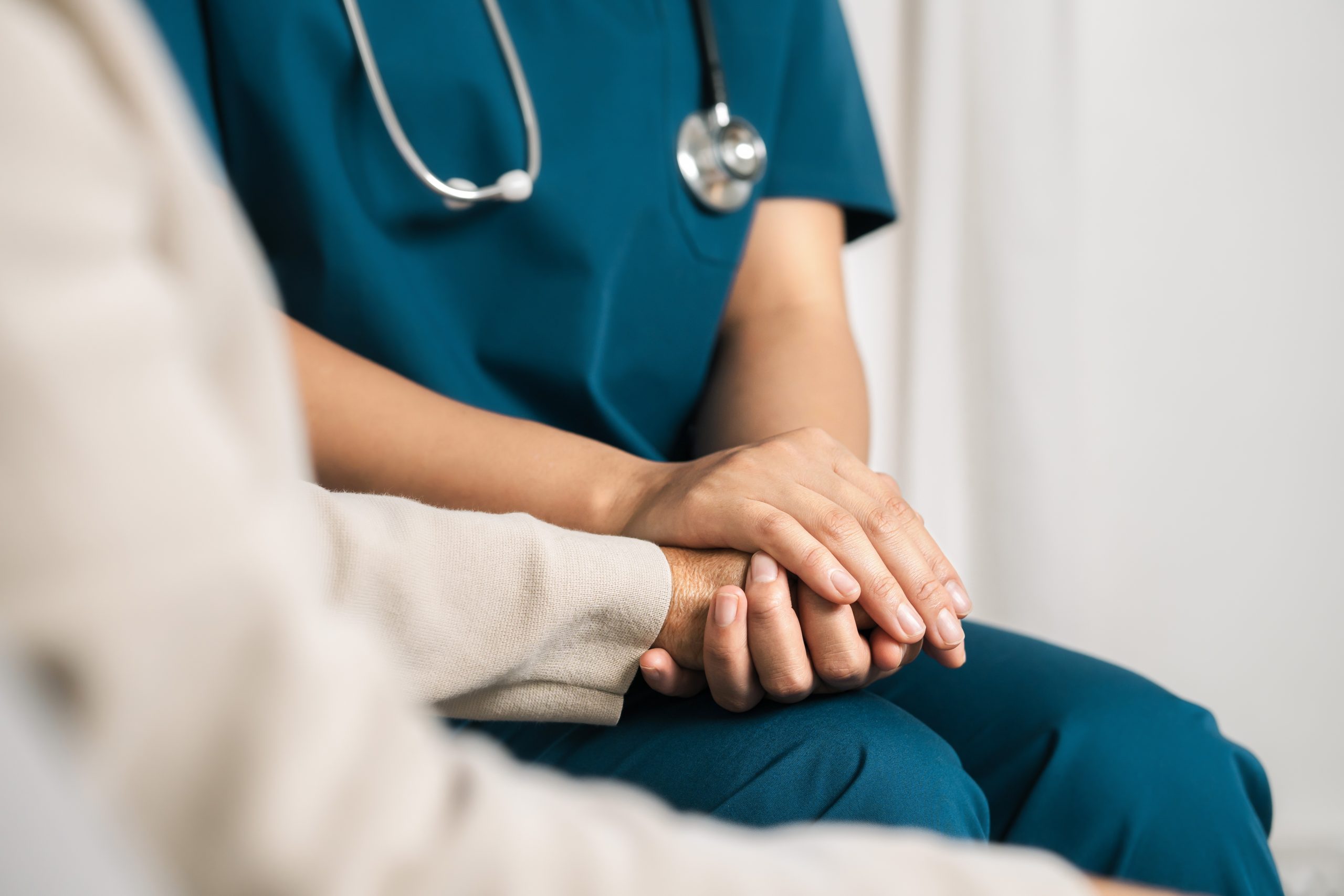 Healthcare worker holding a patient's hand