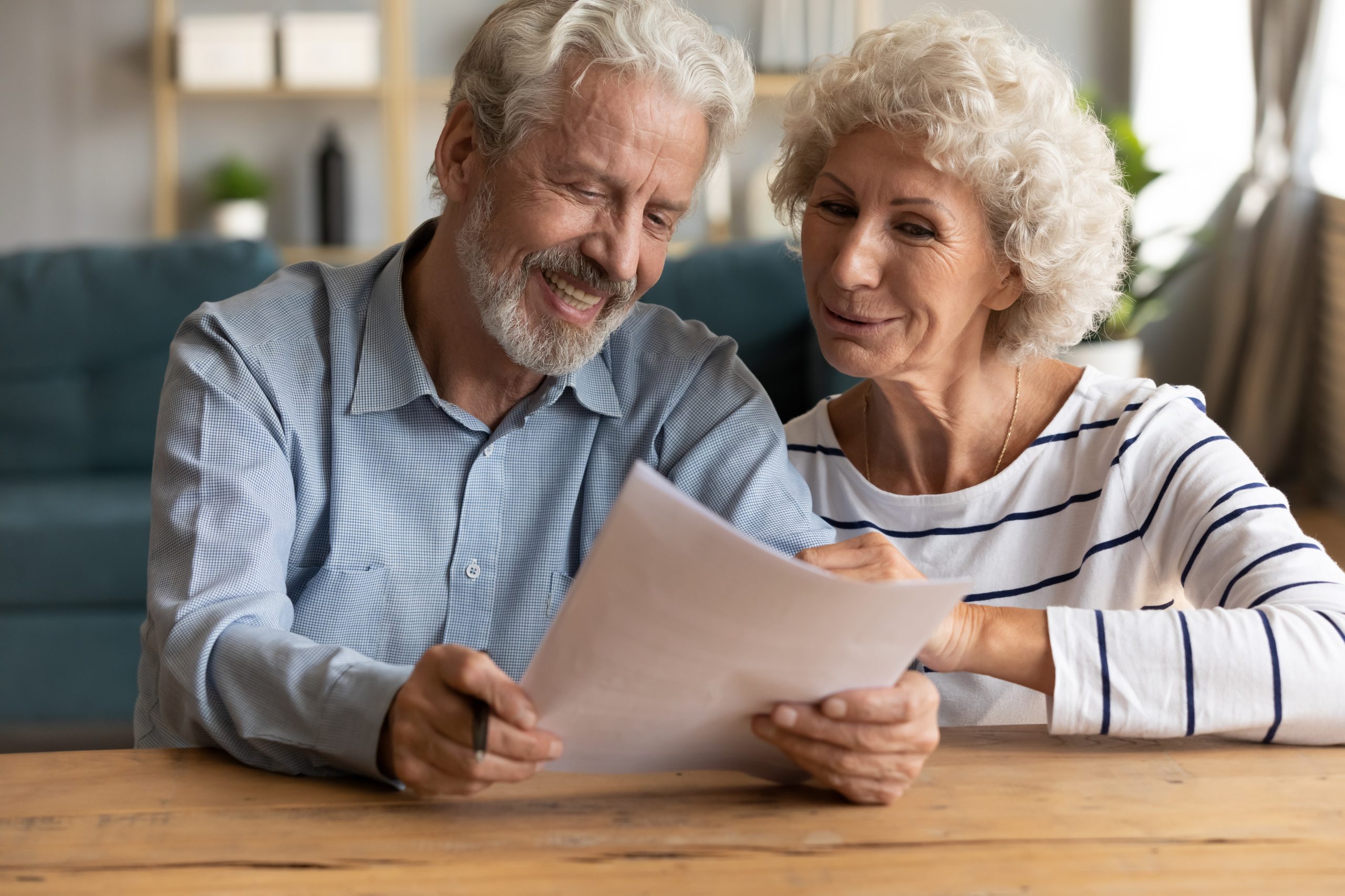 Elderly couple looking at paperwork with smiles on their faces